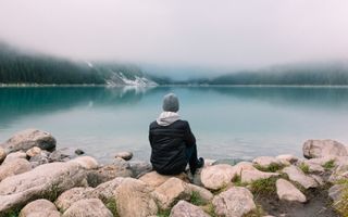 Man sitting on rocks and staring at sea