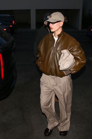 Hailey Bieber in a brown leather bomber jacket and tan pants takes a well-deserved break from their parental duties, indulging in a relaxing spa session at Pellequr Luxury Spa.