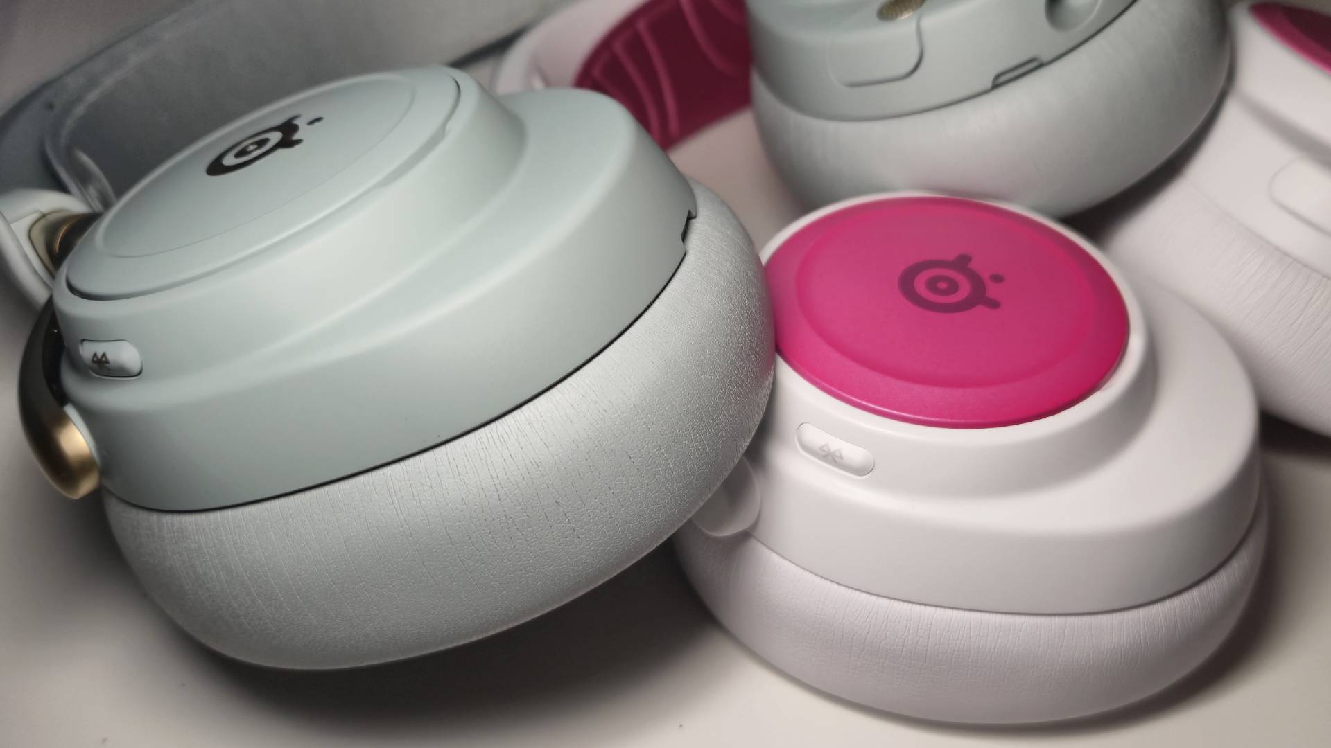 Photo showing the SteelSeries Arctis Nova Elite and the Arctis Nova Pro Wireless sitting next to eachother on a white desk.