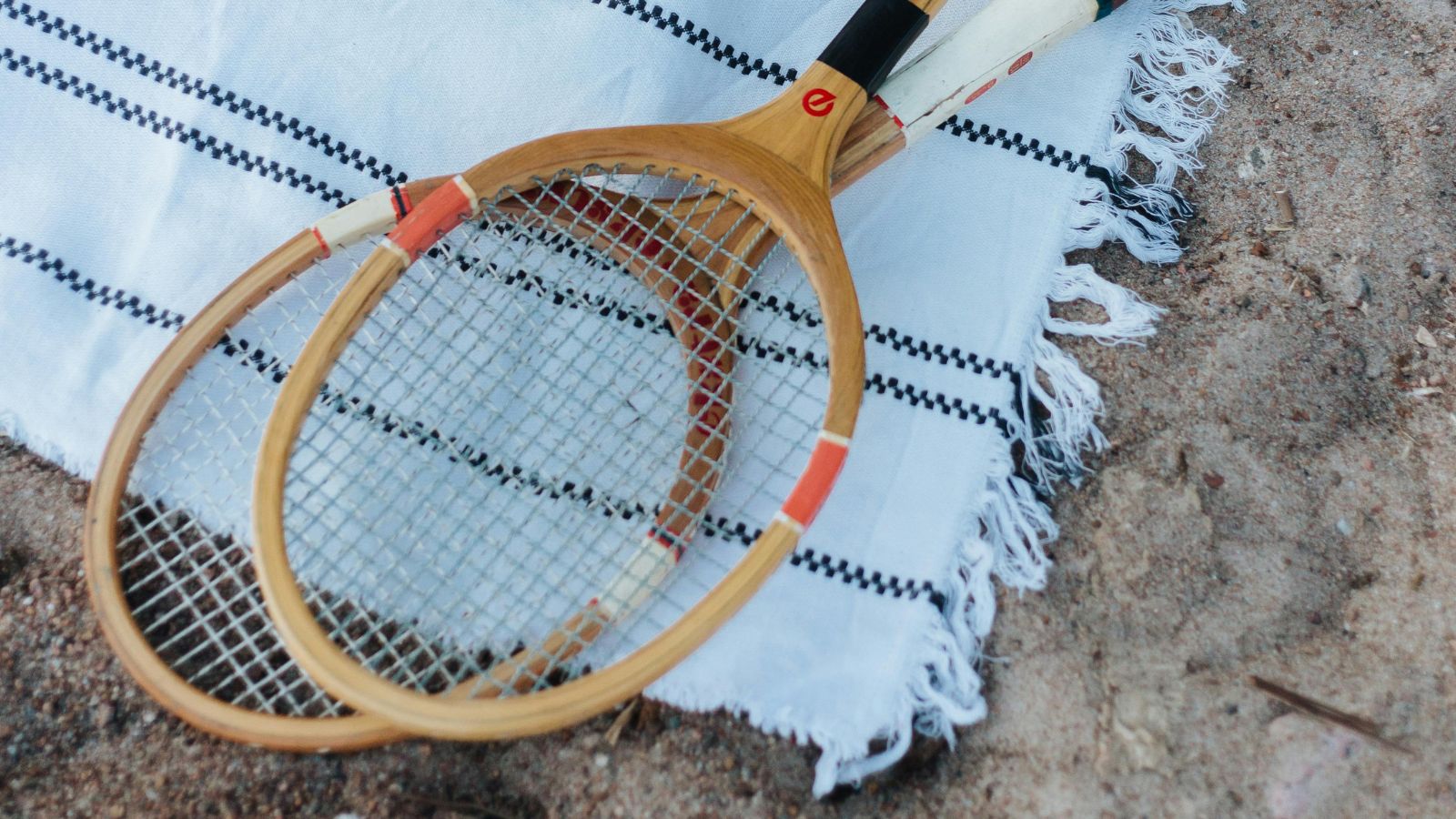 White beach towel with two wooden badminton racquets