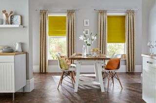 Yellow curtains in dining area with wooden flooring and white wooden table