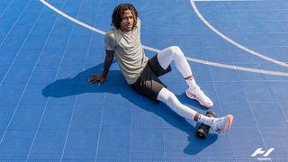 Athelete using a foam roller to roll hic calf on a basketball court