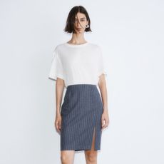 model wears white t-shirt and pinstriped pencil skirt plus black heels with black socks