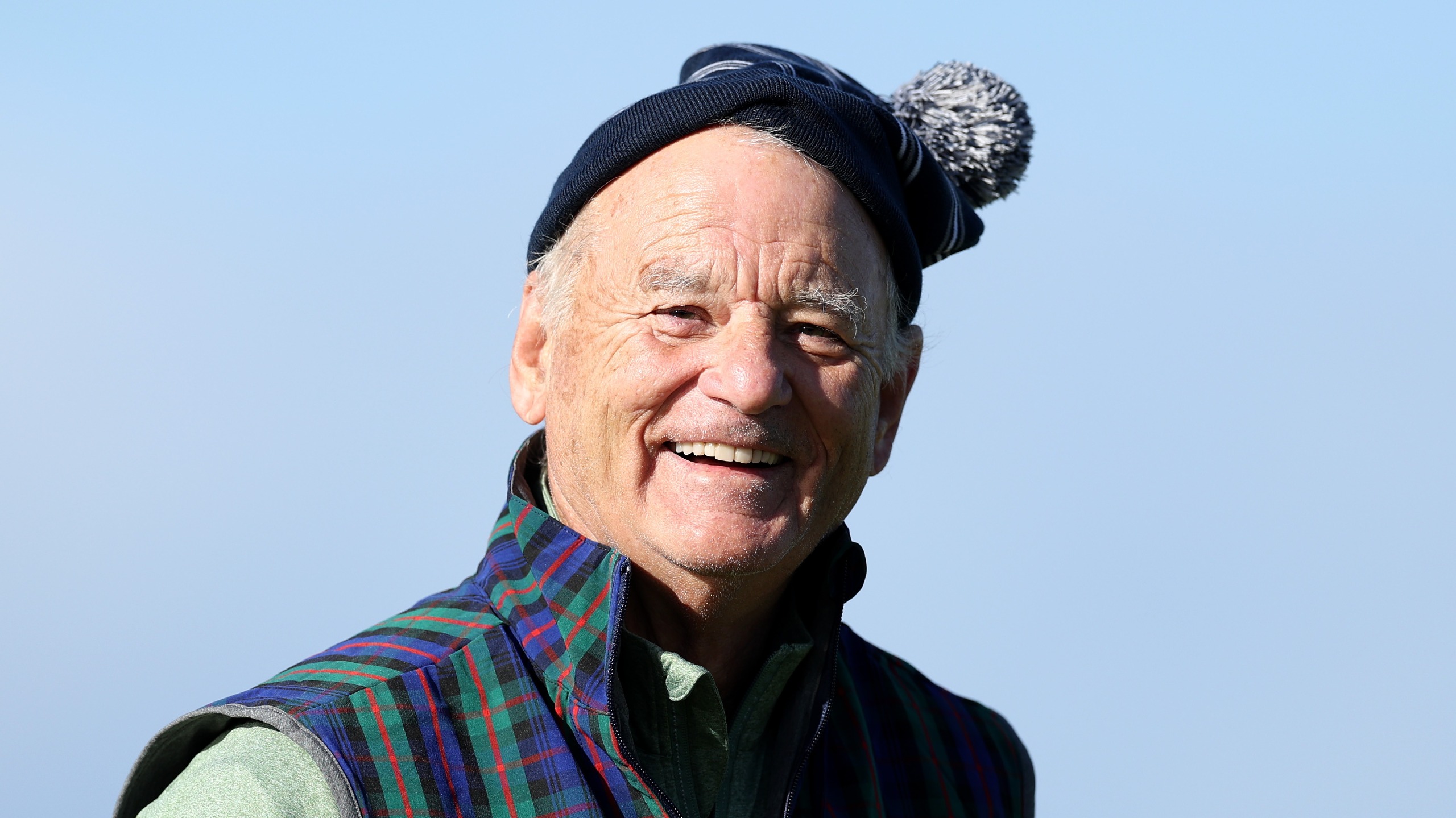 Actor Bill Murray smiles on the 17th green on Day Three of the Alfred Dunhill Links Championship wearing a tartan jacket and hat.