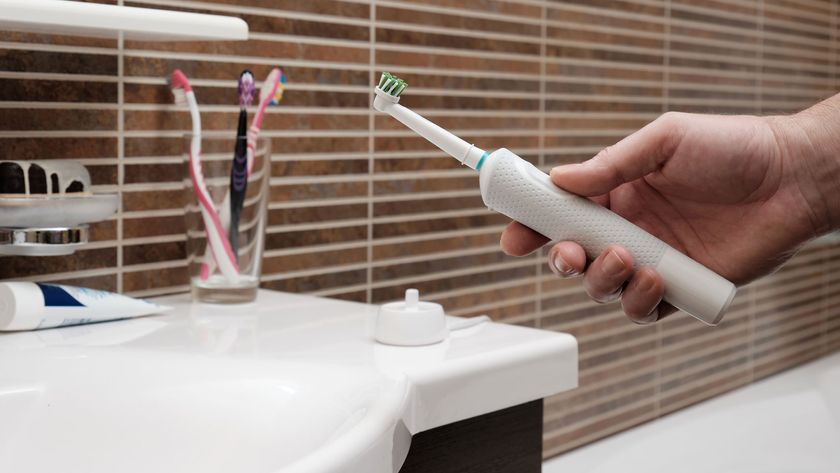 A close-up picture of a man holding an electric toothbrush near the bathroom sink