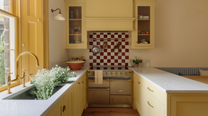 narrow kitchen with butter yellow cabinet, a range cooker, and a tile backsplash