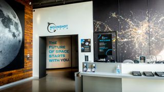 museum exhibit with a large photo of the moon on one wall, next to a doorway, inside of which is written "the future of space starts with you."