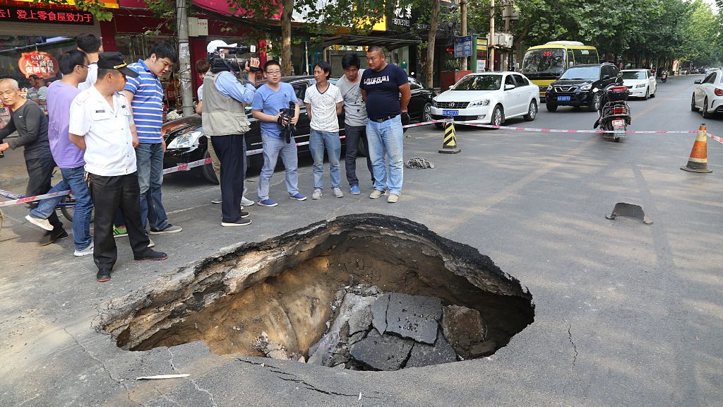 Citizen look at a hole in the road caused by subsidence in Zhenzhou, China.