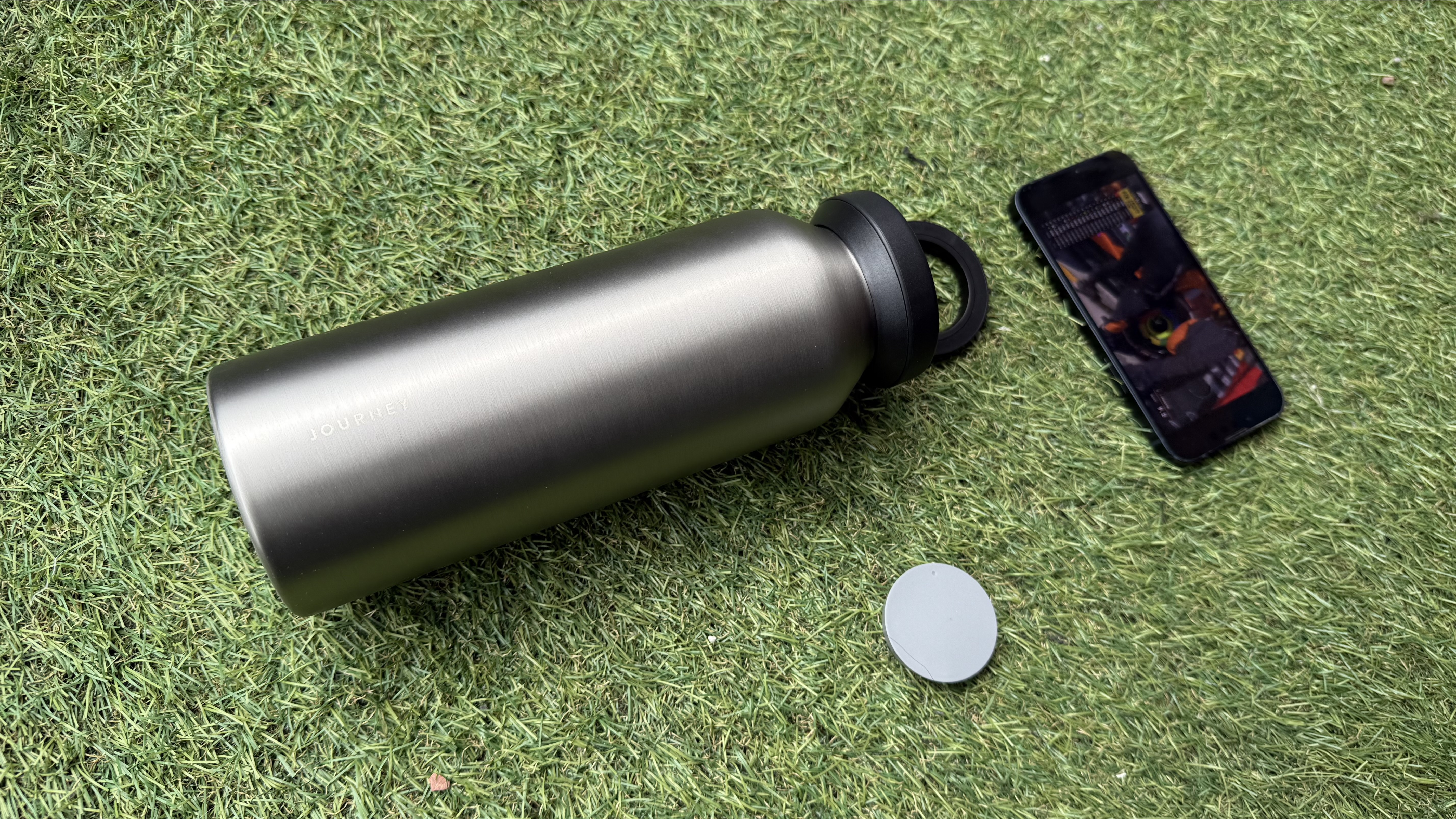The Journey Reevus water bottle on a faux-grass surface