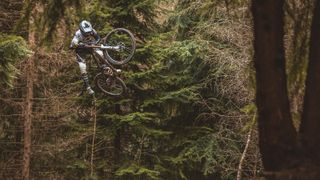 A rider doing a large jump in the forest
