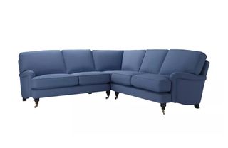 A classic corner sofa with turned wooden legs on castor feet and dark blue linen upholstery