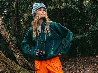 model. wears green fleece orange pants and a hat