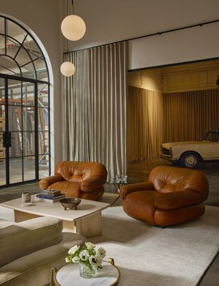 A design showroom features retro-futuristic, plush 1970s furniture, beautiful iron doors and windows, and beige drapery.