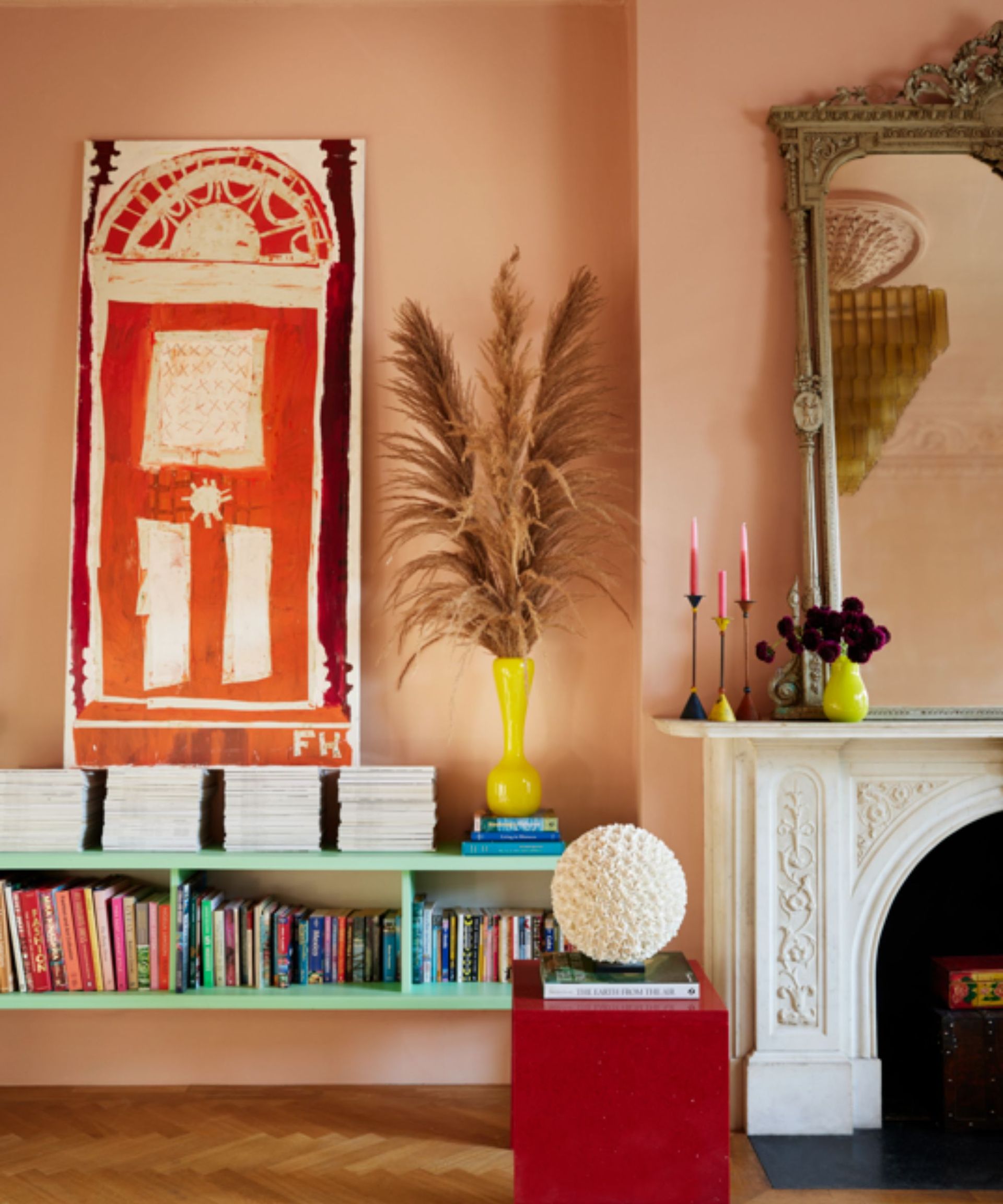 pink living room with ornate white fireplace, red abstract art and green shelves