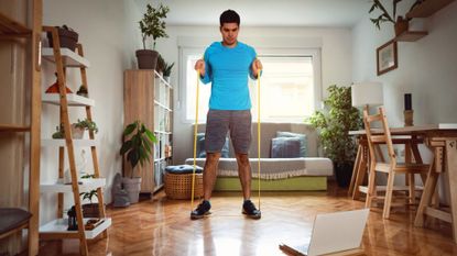 man uses long resistance band for exercise at home