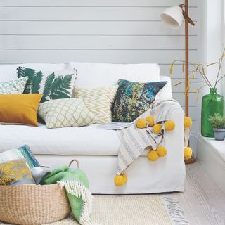 White sofa with throw and cushions with floor lamp