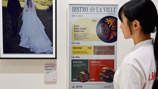 A woman looking at a menu displayed on an LG e-paper platform.
