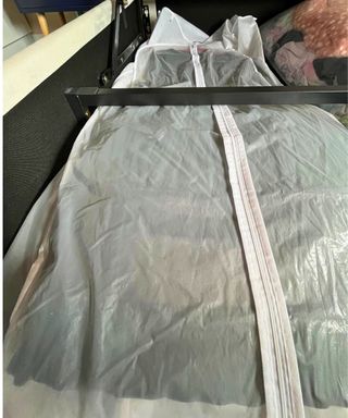 White garment bag with zip laying flat on its hanger inside my ottoman bed