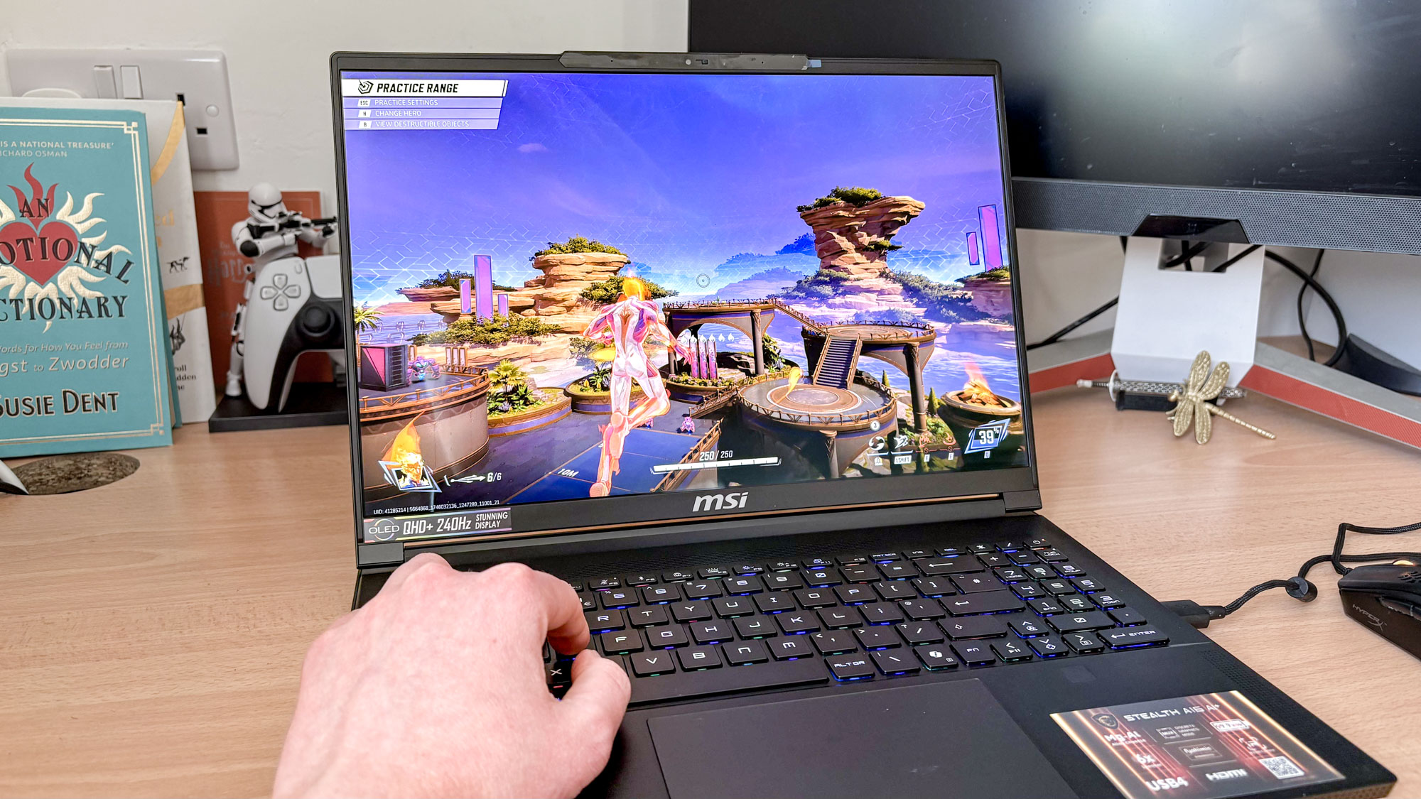 MSI Stealth A16 AI+ on desk with Marvel Rivals on display with hand on keyboard