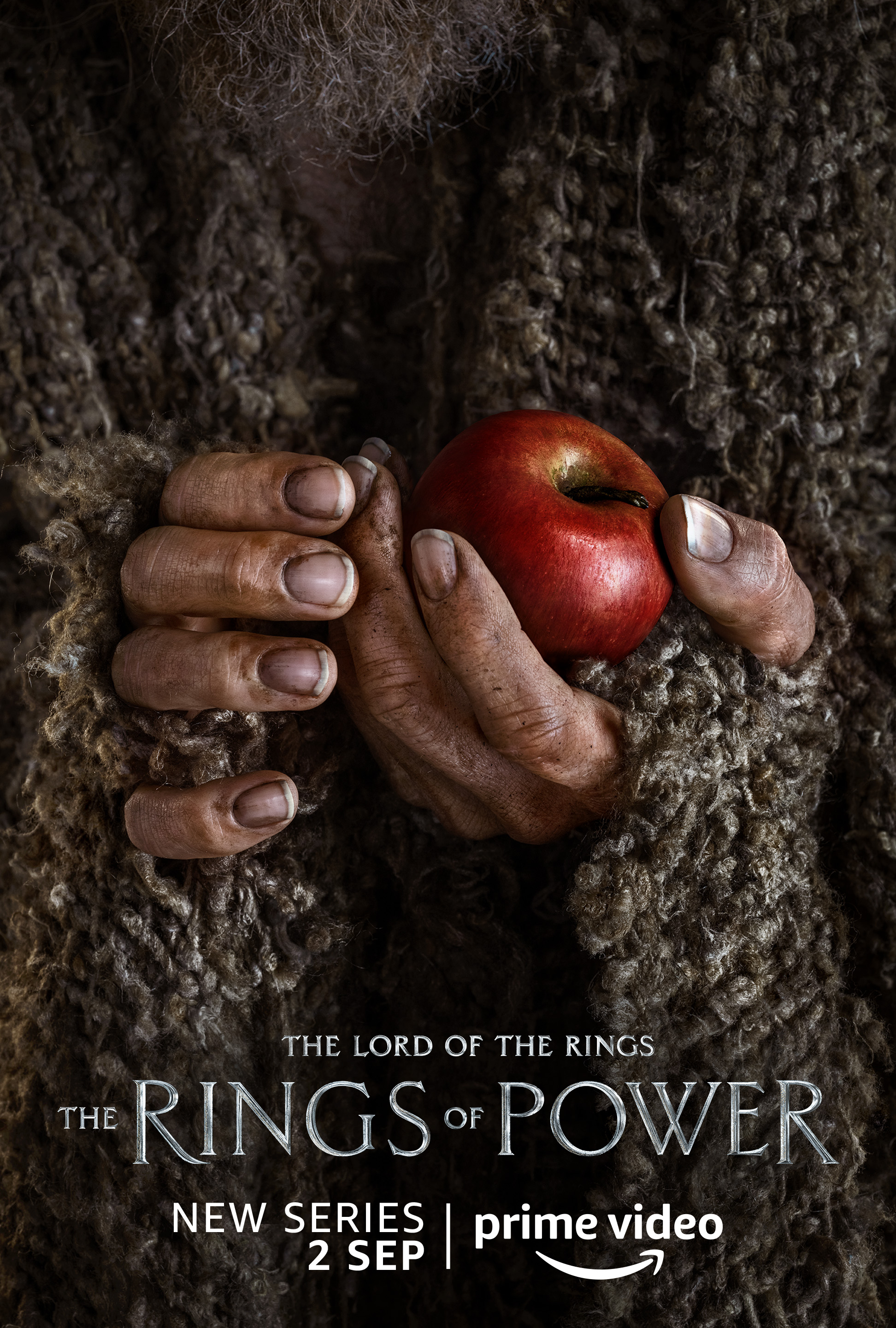 A human holding an apple character poster for Lord of the Rings: The Rings of Power