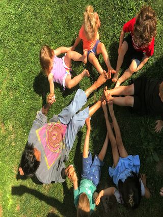 A circle of children putting their feet together