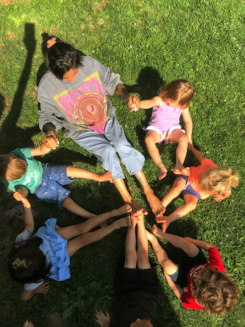 A circle of children putting their feet together