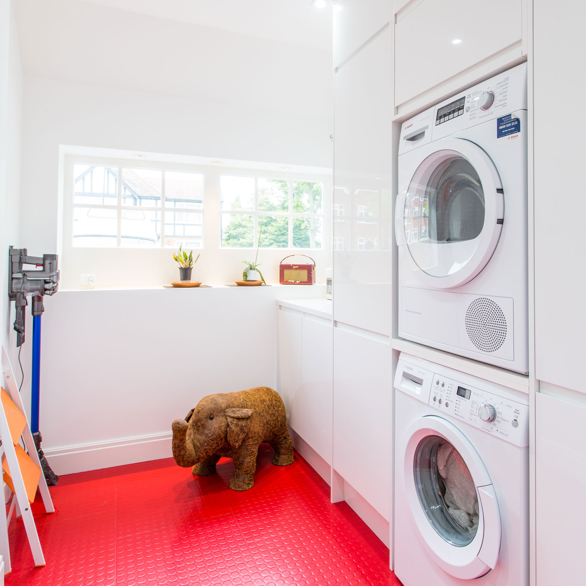 garage conversion utility room with stacked appliances and red rubber flooring