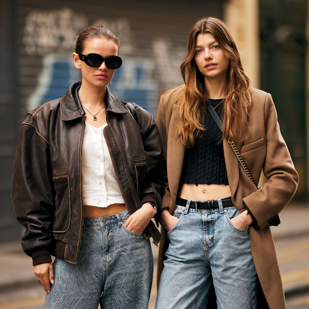 two fashion week attendees wear brown coats and jackets with denim