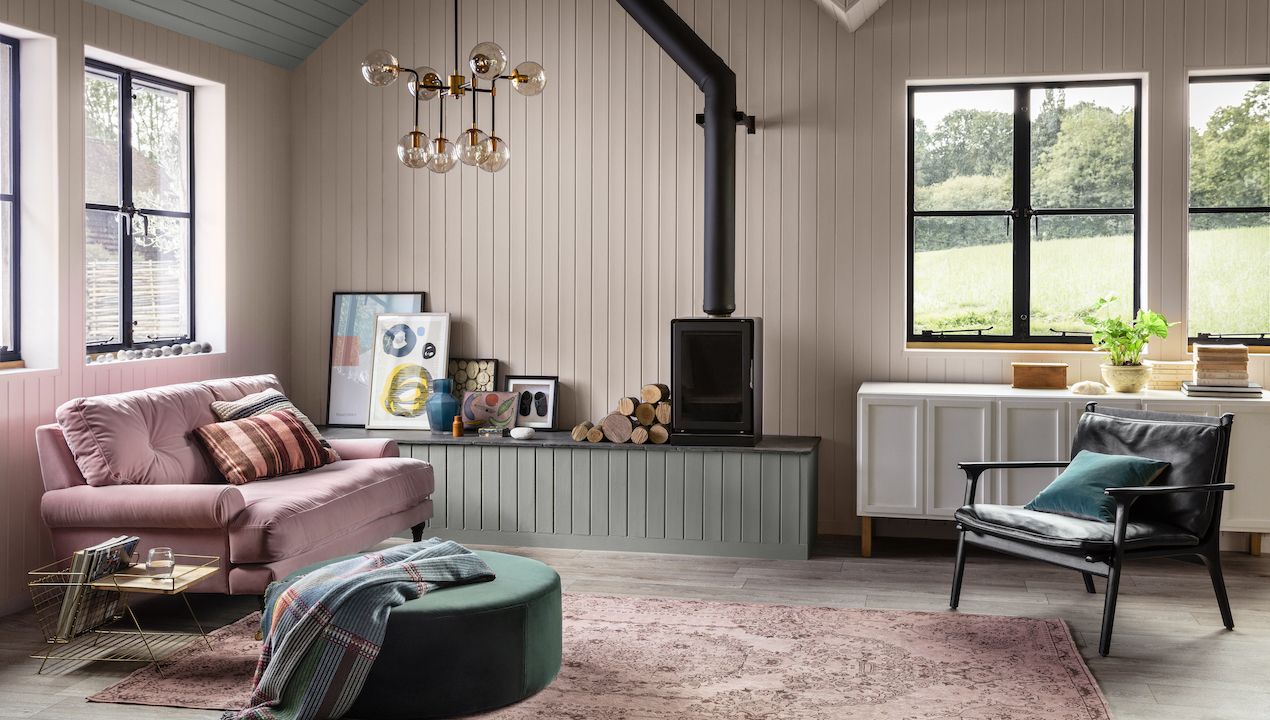 living room with woodburner and pink walls, pink sofa and retro chair