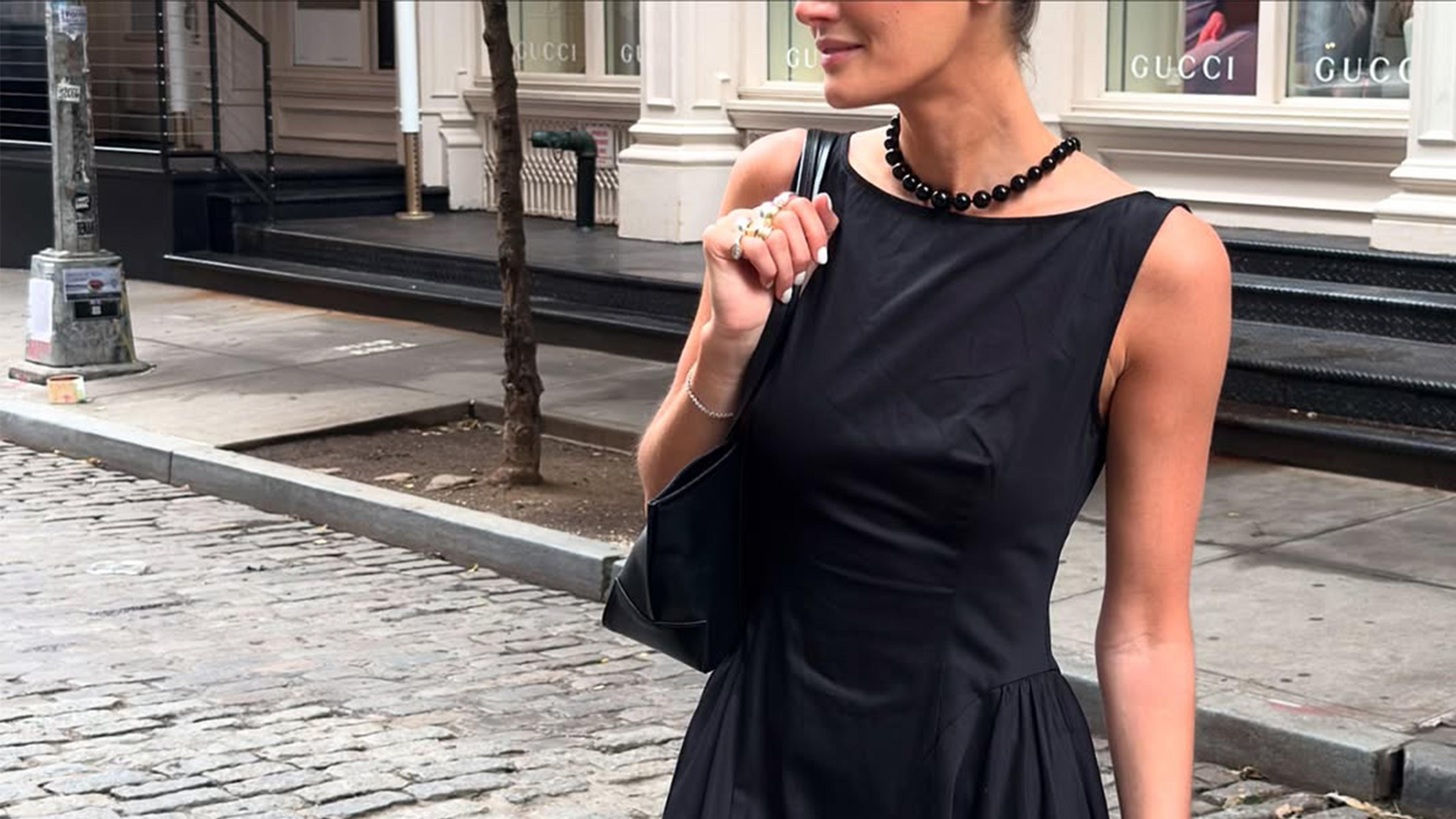 Coco Schiffer wearing a black dress, necklace, and bag.