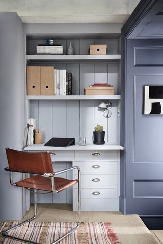 A pale blue office space with built in shelving