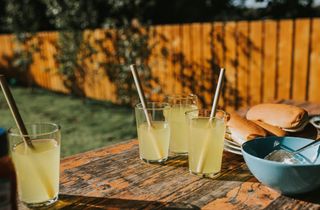 Diluted orange juice in glasses with bamboo straws on a picnic table.