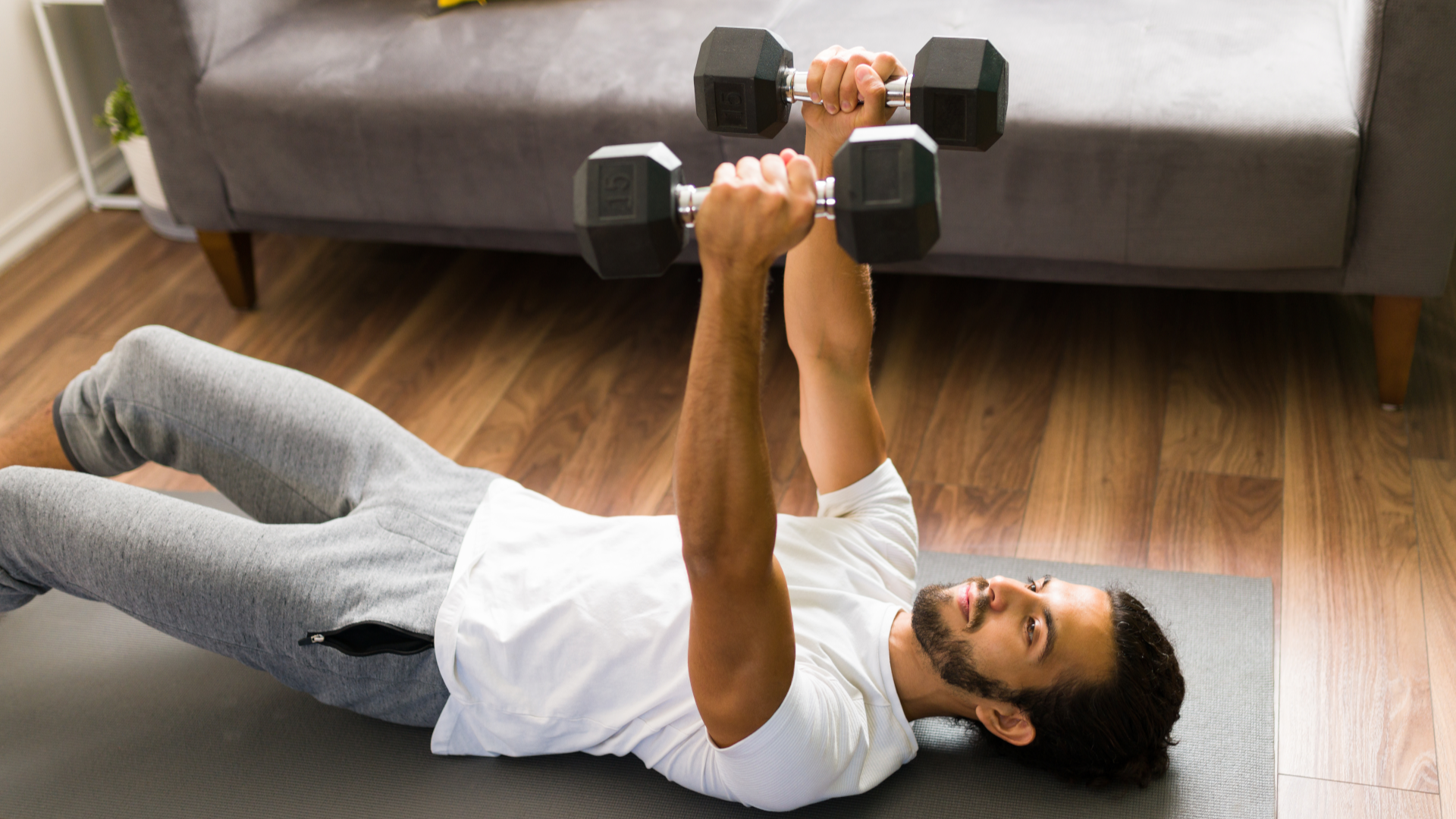 A man performing dumbbell floor press in his living room