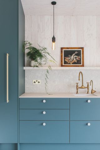 Blue kitchen by Husk with white worktops and gold/bronze fixtures