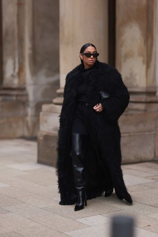 woman wearing a faux fur coat, black top, pants, and boots