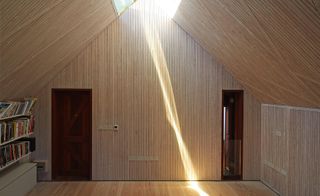 Skylights continue down the length of the pitched roof, softly illuminating the white larch lining of the top floor study space