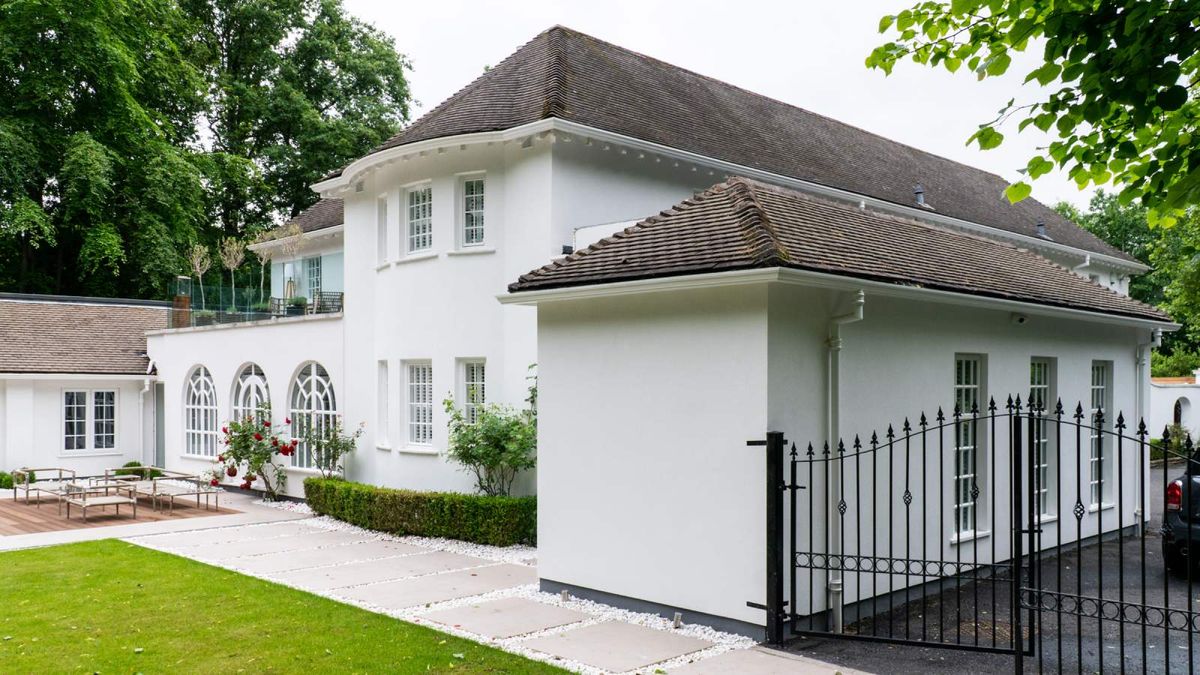 Large detached white rendered traditional-style house with clay roof tiles and smart rainwater good matching the exterior