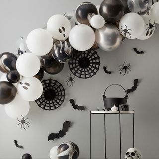 Halloween black and white balloon arch against grey wall with bats and spiders