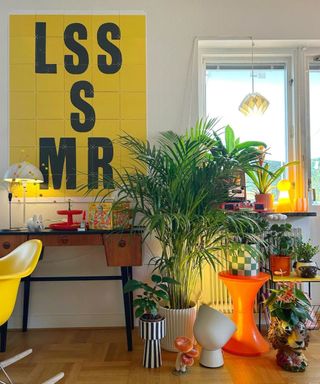 A living space with a yellow poster and colorful tables and plants