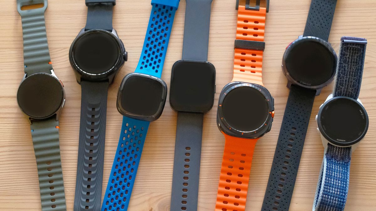 A table with a dozen similar smartwatches on it