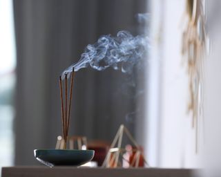 Incense sticks smoldering in an incense burner on table indoors