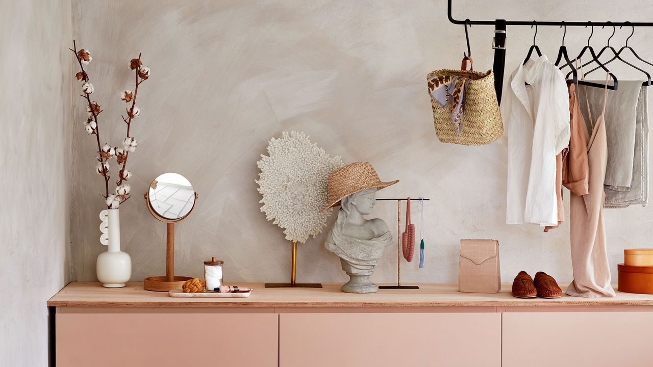 Dressing room with black clothes hanging rail above pink drawers