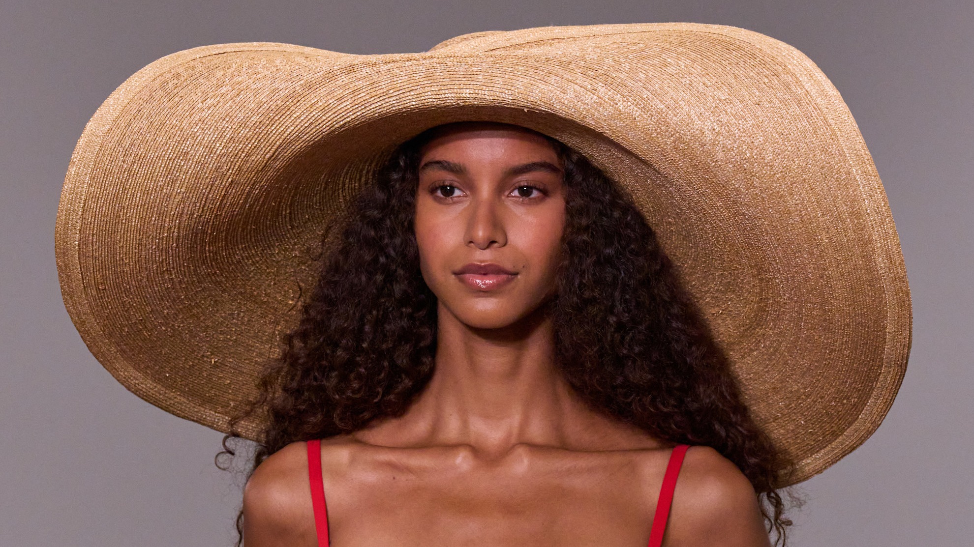 a model with clean skin wearing a large hat