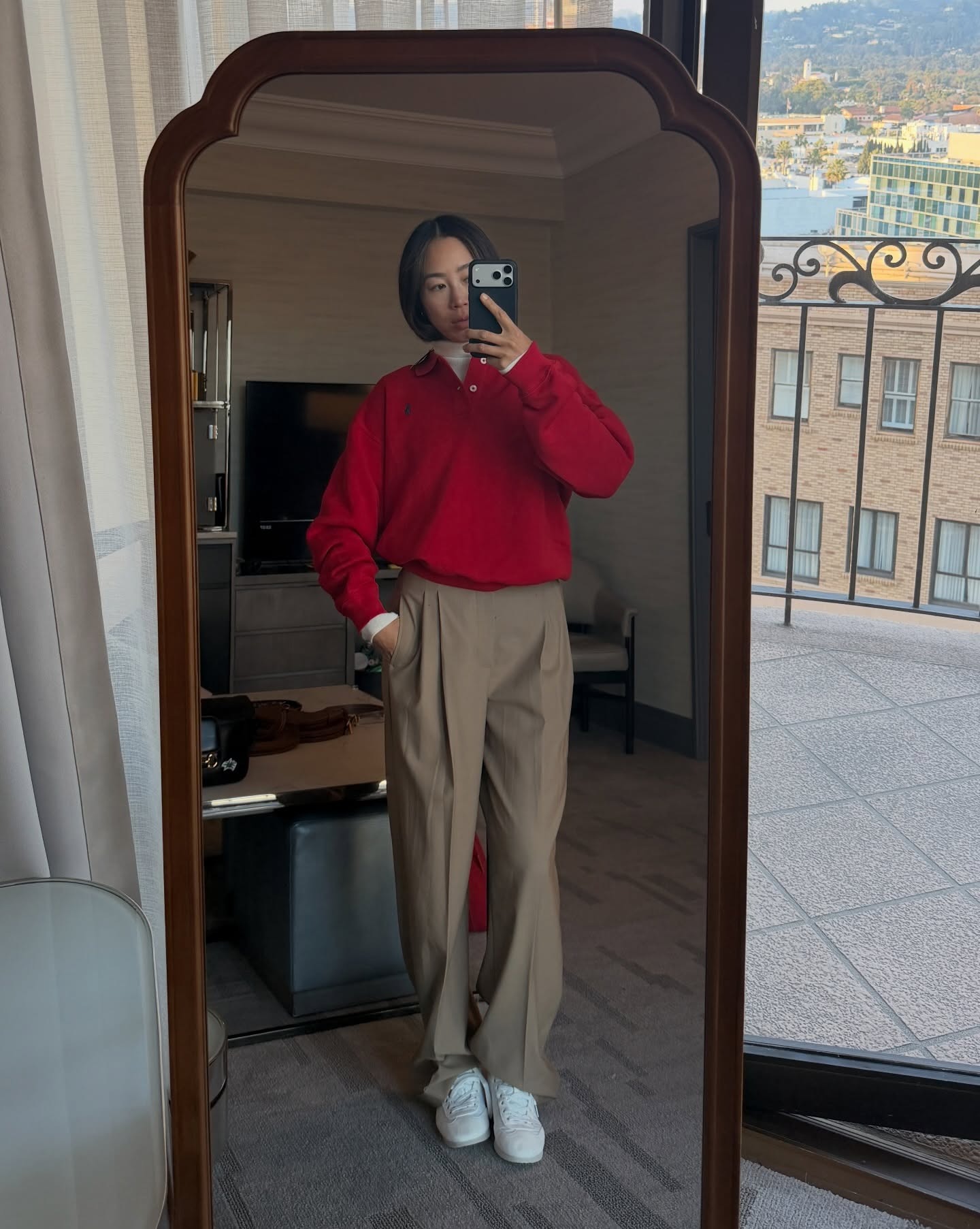 Woman in red sweater, beige pants, and white sneakers