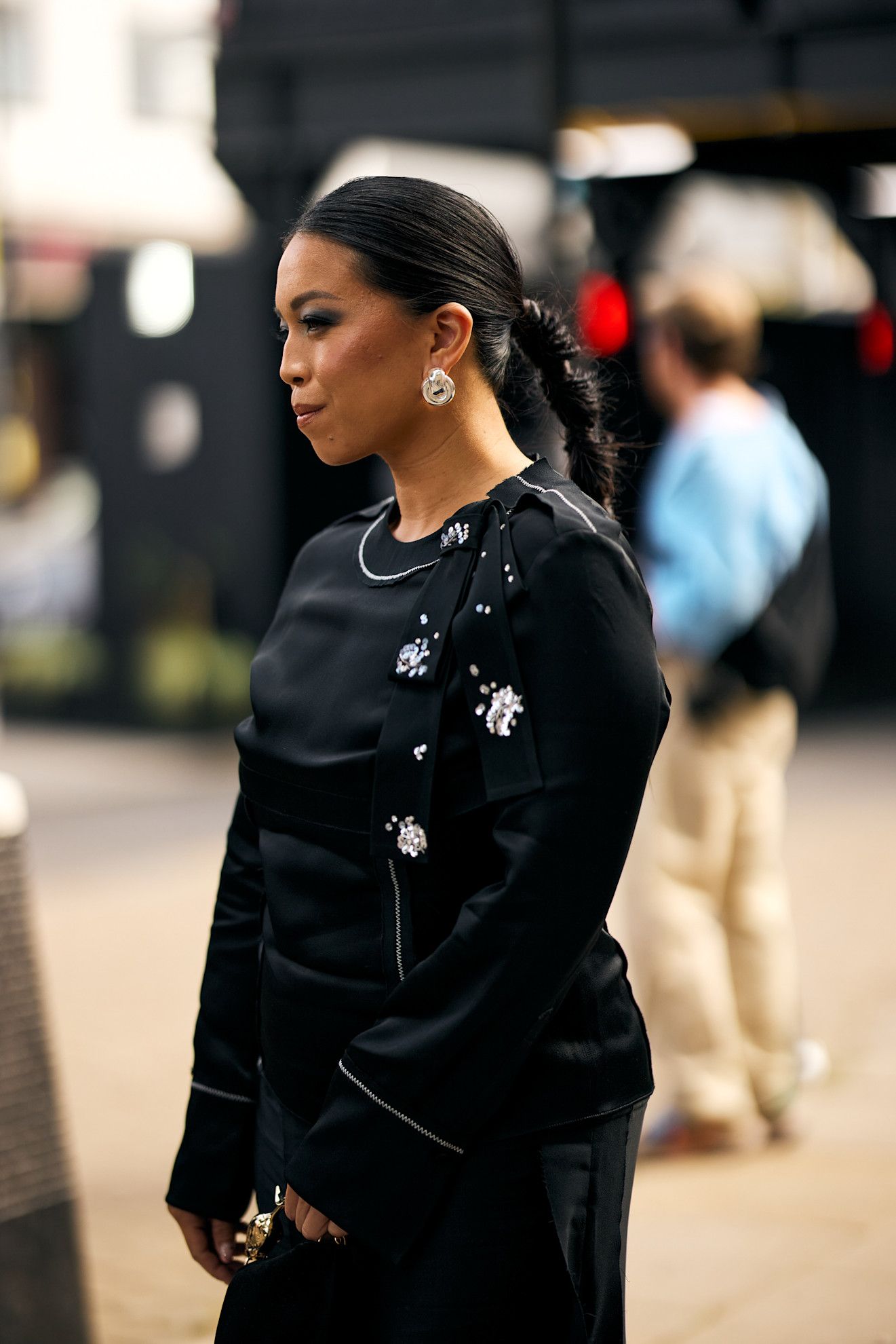 an asian woman in a black jacket with pins and her hair in a braid