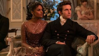 Jonathan Bailey and Simone Ashley as Anthony and Kate, sitting down at social function
