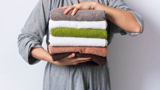 Women holding pile of towels 