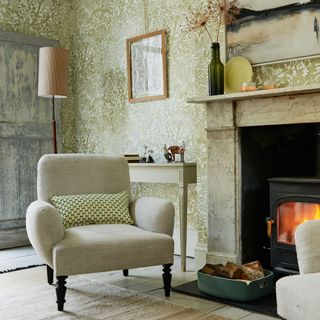 A country living room with leafy green print wallpaper and a cream armchair
