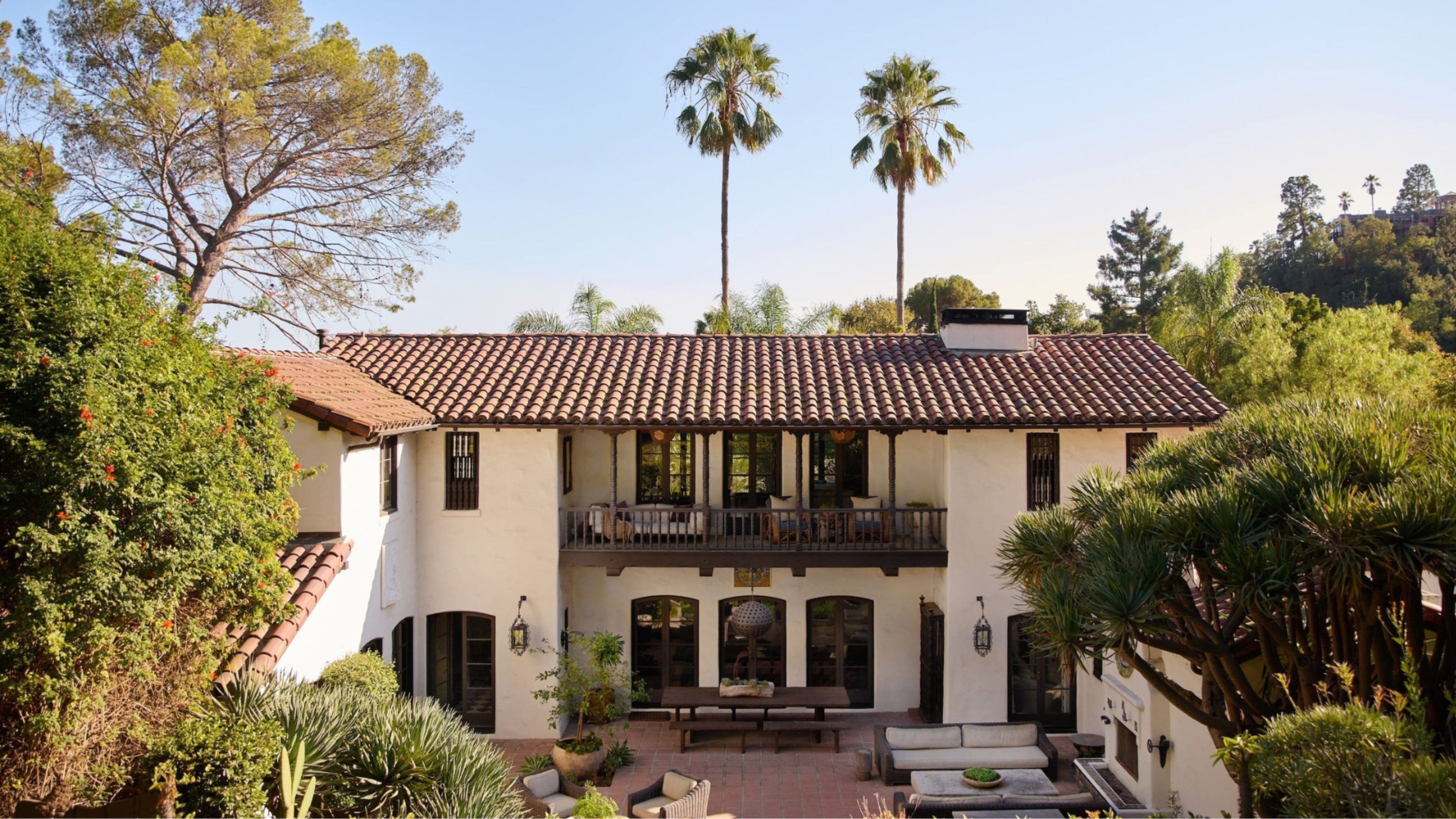 Large spanish colonial style house surrounded by trees.