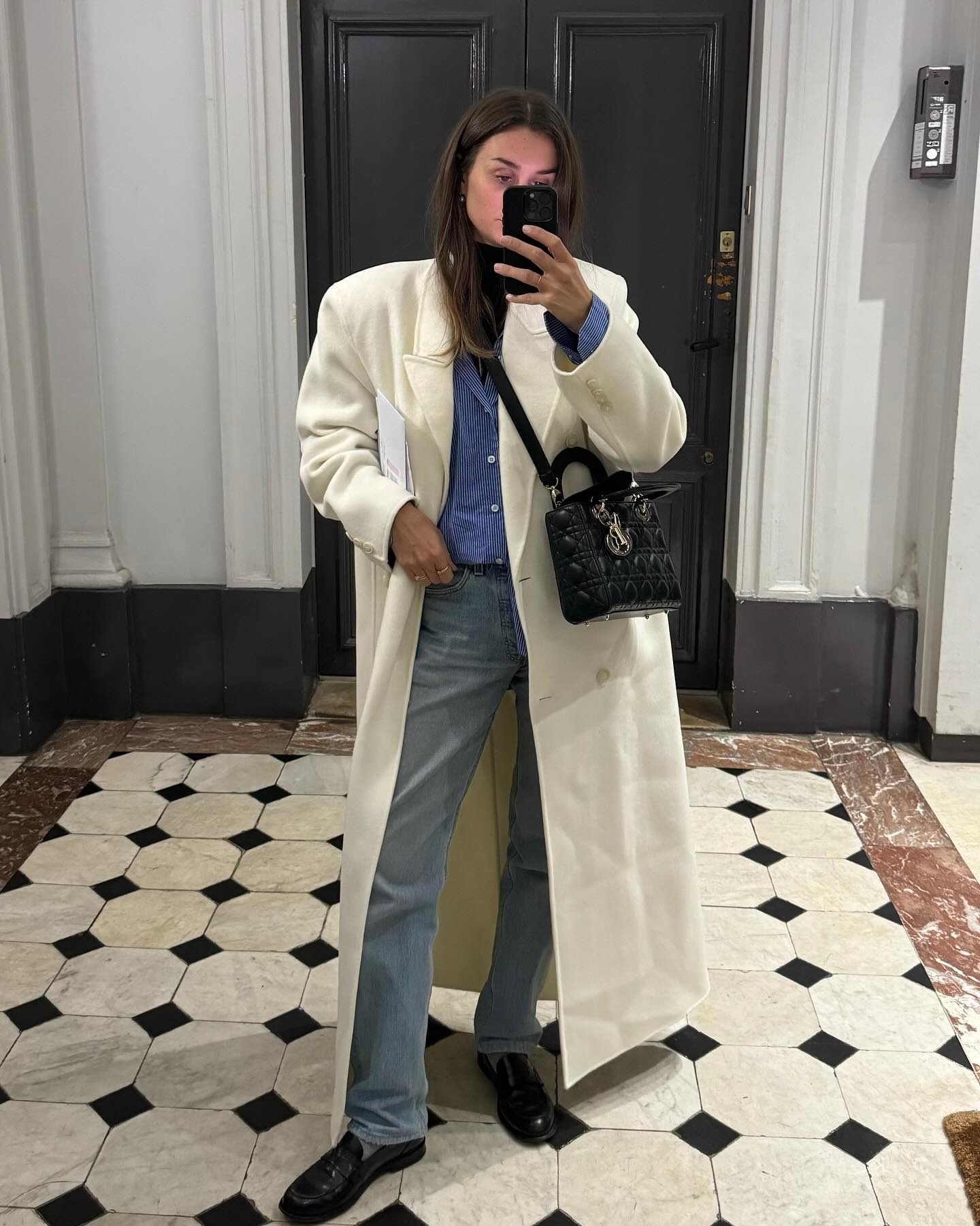 @annelauremais wearing a cream coat with a blue shirt and jeans.